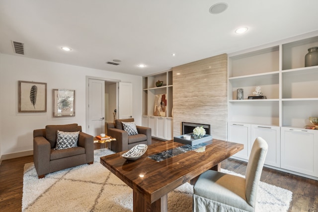 living room featuring dark hardwood / wood-style floors, a fireplace, and built in features