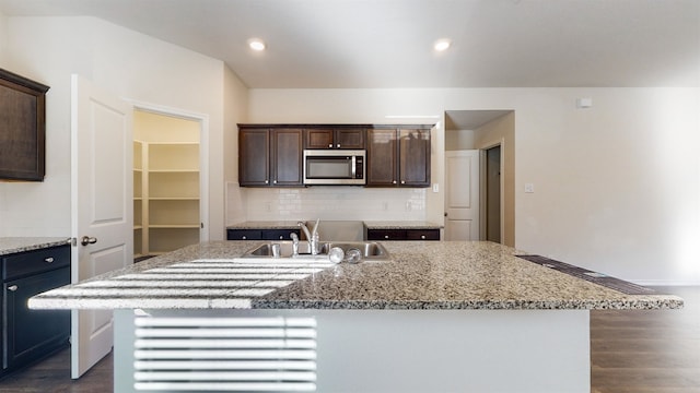 kitchen featuring dark brown cabinets, sink, a center island with sink, and dark hardwood / wood-style flooring