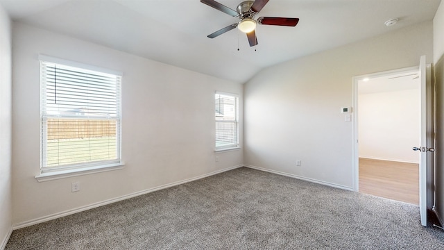 carpeted spare room featuring lofted ceiling and ceiling fan