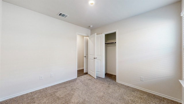 unfurnished bedroom with a closet and light colored carpet