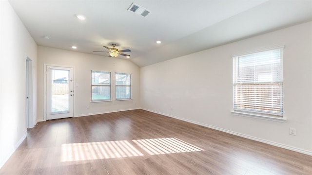 spare room featuring wood-type flooring, plenty of natural light, and vaulted ceiling