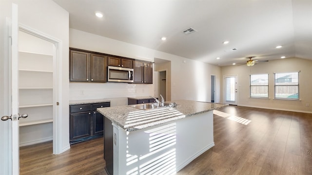 kitchen with a center island with sink, sink, ceiling fan, dark brown cabinetry, and dark hardwood / wood-style floors