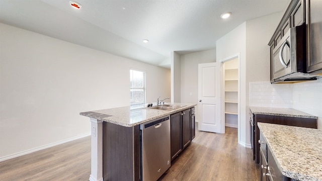 kitchen featuring appliances with stainless steel finishes, a kitchen island with sink, sink, and wood-type flooring