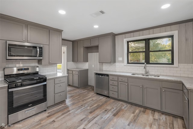 kitchen featuring gray cabinetry, sink, light hardwood / wood-style flooring, and appliances with stainless steel finishes