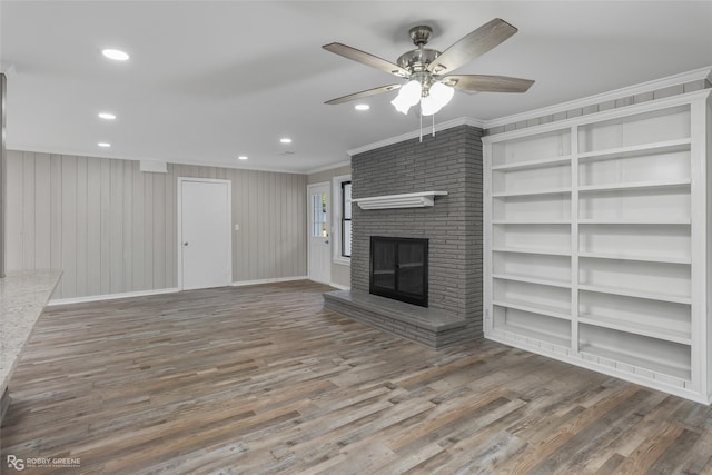 unfurnished living room with ceiling fan, ornamental molding, dark hardwood / wood-style floors, and a brick fireplace