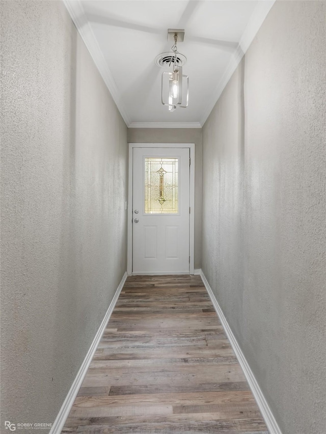 doorway to outside featuring a chandelier, light hardwood / wood-style floors, and crown molding