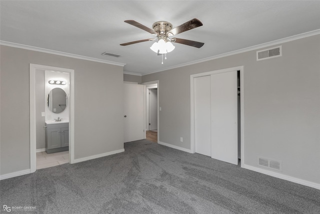 unfurnished bedroom with ensuite bathroom, light colored carpet, ceiling fan, crown molding, and a closet