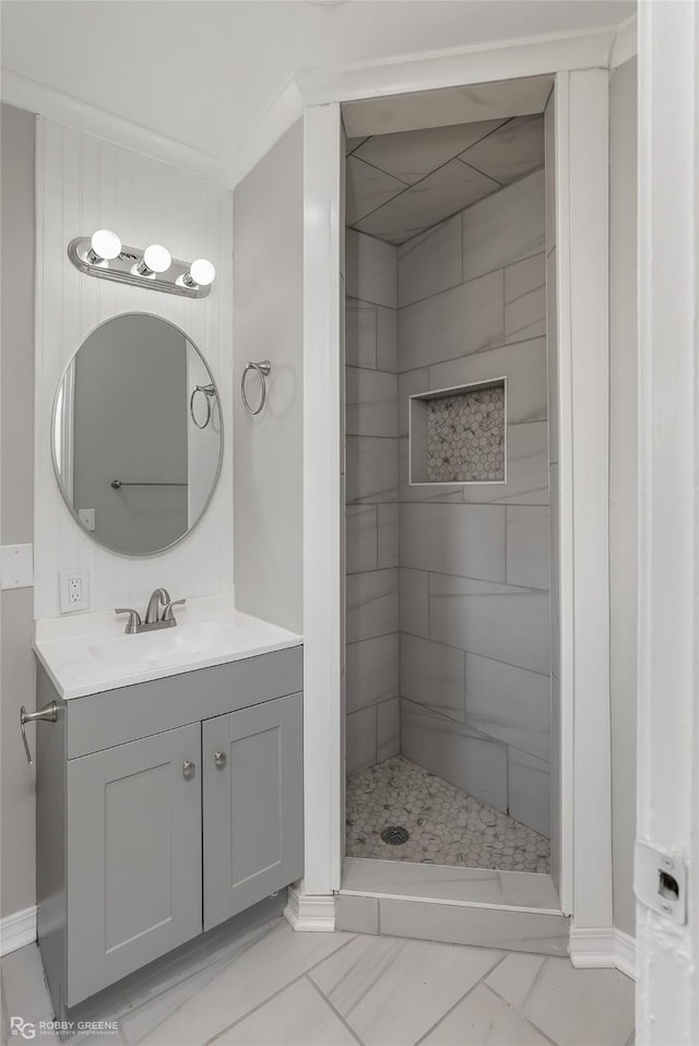 bathroom featuring a tile shower, crown molding, and vanity