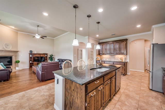 kitchen with ceiling fan, sink, decorative light fixtures, a center island with sink, and crown molding