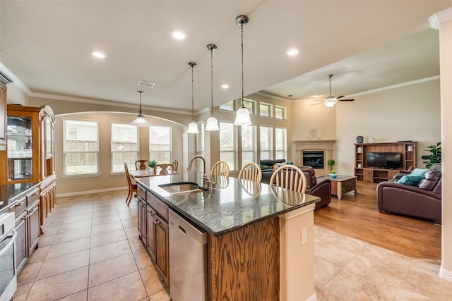 kitchen featuring dark stone counters, sink, an island with sink, hanging light fixtures, and appliances with stainless steel finishes