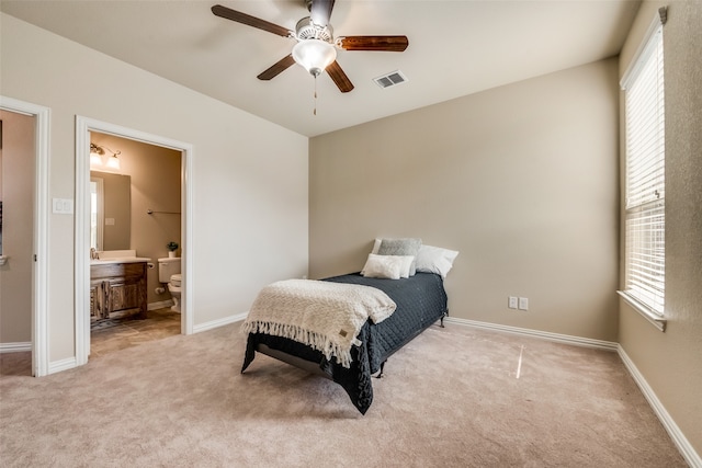 bedroom featuring ceiling fan, connected bathroom, and light carpet