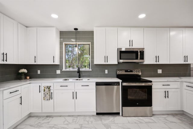 kitchen featuring hanging light fixtures, white cabinetry, sink, and appliances with stainless steel finishes