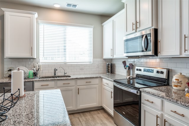 kitchen with appliances with stainless steel finishes, white cabinetry, and tasteful backsplash