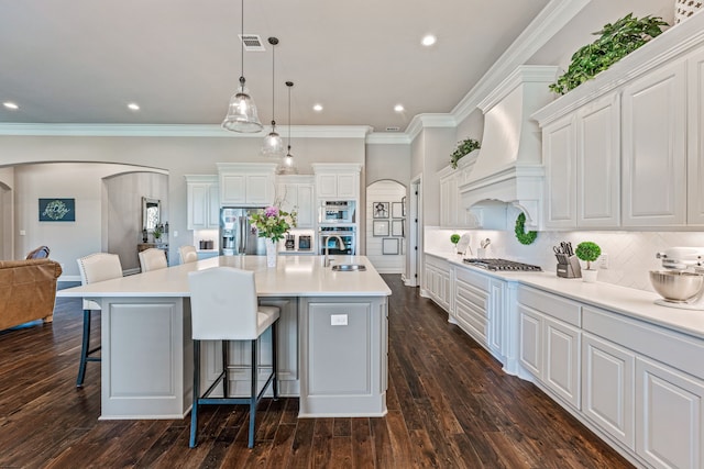 kitchen featuring a sink, custom range hood, appliances with stainless steel finishes, and arched walkways