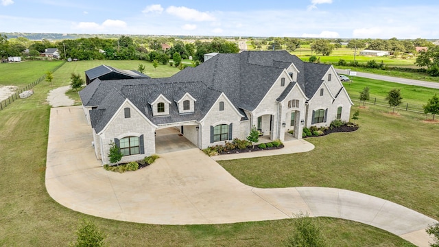 french country inspired facade with curved driveway, roof with shingles, fence, a front lawn, and brick siding