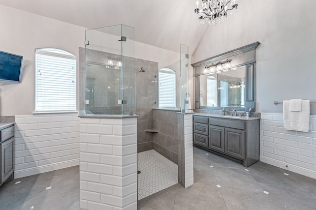 bathroom featuring tile walls, vanity, a tile shower, lofted ceiling, and tile patterned floors