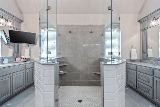 bathroom with a tile shower, a wealth of natural light, and vanity