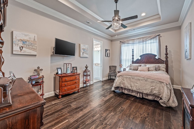 bedroom featuring dark hardwood / wood-style flooring, a tray ceiling, ensuite bathroom, crown molding, and ceiling fan