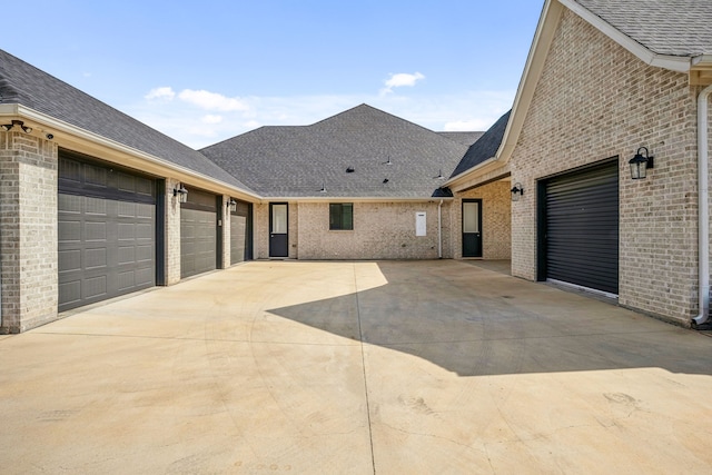 view of property exterior with roof with shingles, concrete driveway, a garage, and brick siding