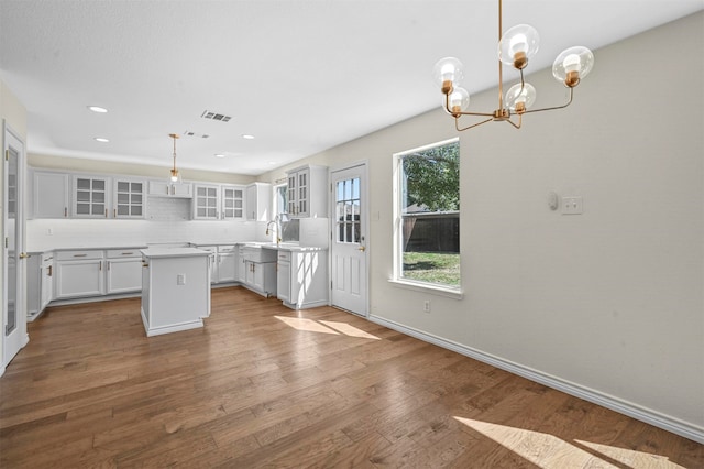 kitchen featuring hanging light fixtures, a kitchen island, white cabinetry, light hardwood / wood-style floors, and a notable chandelier