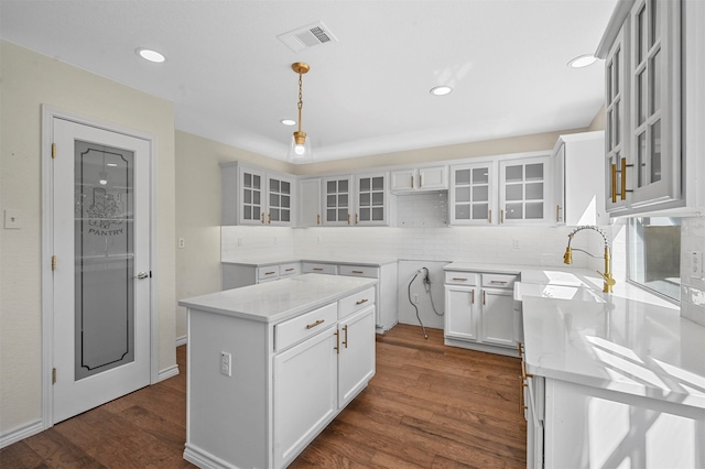 kitchen with dark hardwood / wood-style flooring, white cabinetry, a center island, sink, and decorative light fixtures