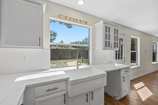 kitchen with white cabinetry, dark hardwood / wood-style floors, tasteful backsplash, and light stone counters