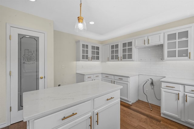 kitchen with decorative backsplash, white cabinetry, light stone countertops, dark wood-type flooring, and pendant lighting