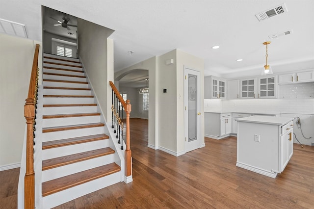 kitchen with tasteful backsplash, wood-type flooring, a kitchen island, hanging light fixtures, and white cabinets