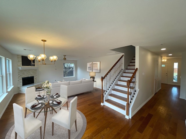 dining room featuring a notable chandelier, a fireplace, and dark hardwood / wood-style floors