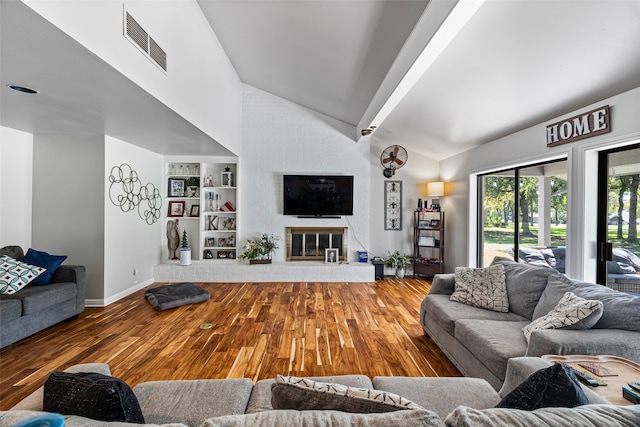 living room featuring a brick fireplace, lofted ceiling, built in features, and wood-type flooring