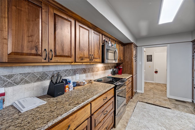 kitchen with appliances with stainless steel finishes, decorative backsplash, and stone counters