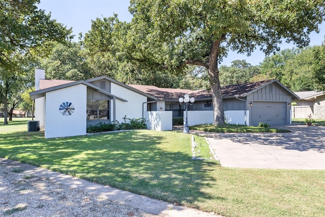 ranch-style home with a front yard, a garage, and central AC unit