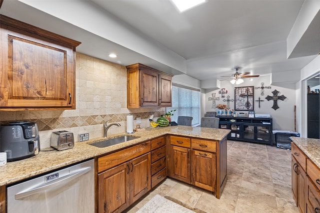 kitchen with light stone counters, kitchen peninsula, dishwasher, ceiling fan, and sink