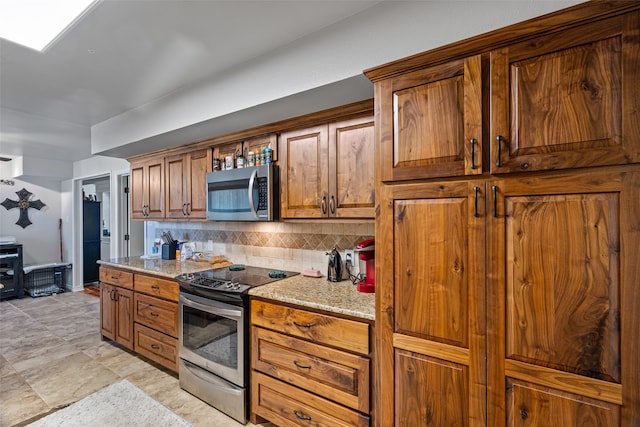 kitchen with light stone countertops, stainless steel appliances, and decorative backsplash