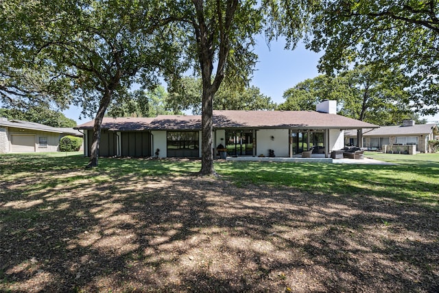 view of front facade with a front yard, a garage, and a patio area