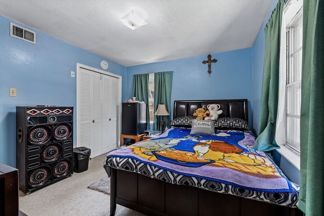 carpeted bedroom with a closet, multiple windows, and a textured ceiling