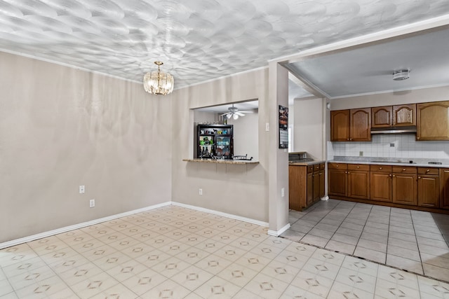 kitchen featuring pendant lighting, tasteful backsplash, ceiling fan with notable chandelier, black cooktop, and ornamental molding