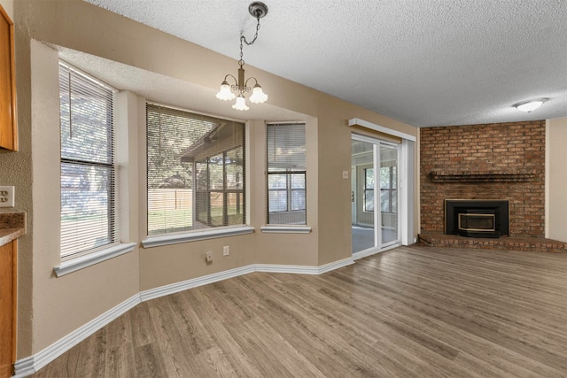 unfurnished living room featuring a textured ceiling, hardwood / wood-style floors, a chandelier, and a wealth of natural light