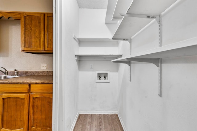 laundry room featuring cabinets, light hardwood / wood-style floors, hookup for a washing machine, and sink