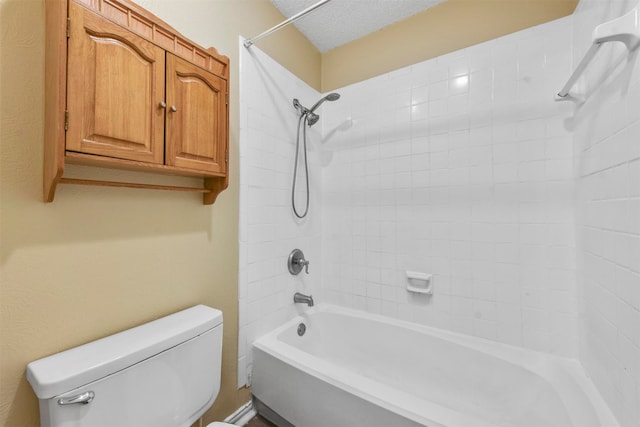 bathroom featuring a textured ceiling, tiled shower / bath, and toilet