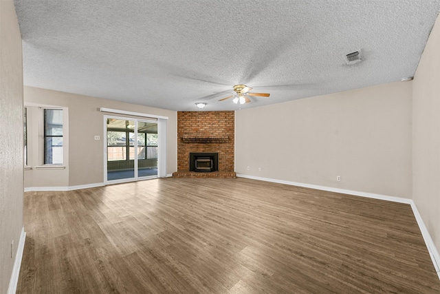 unfurnished living room with ceiling fan, a textured ceiling, a fireplace, and hardwood / wood-style floors