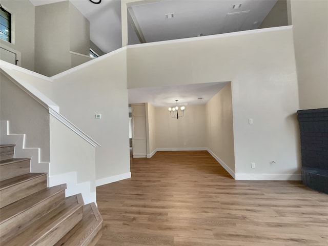 interior space featuring a notable chandelier, light hardwood / wood-style floors, and a high ceiling