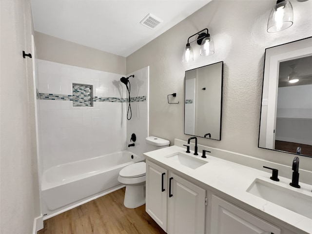 full bathroom featuring wood-type flooring, tiled shower / bath combo, vanity, and toilet