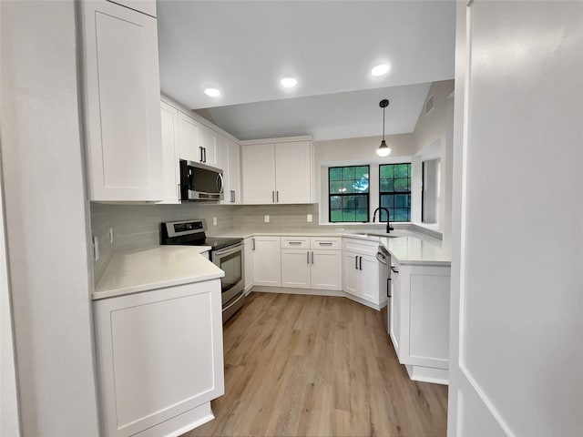 kitchen featuring light hardwood / wood-style floors, sink, white cabinets, stainless steel appliances, and decorative light fixtures