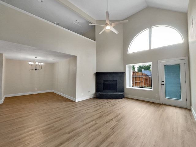 unfurnished living room with ceiling fan with notable chandelier, high vaulted ceiling, light hardwood / wood-style flooring, and a fireplace