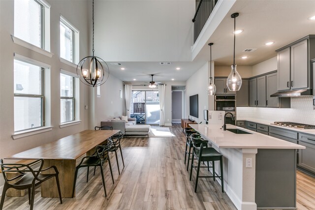 kitchen with light countertops, gray cabinets, appliances with stainless steel finishes, light wood-style floors, and a sink