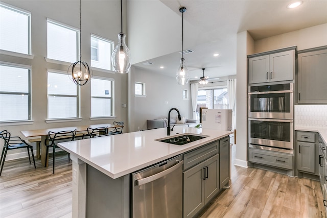 kitchen featuring gray cabinets, stainless steel appliances, light countertops, and a sink