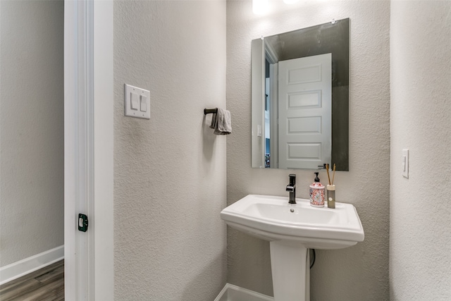 bathroom with a textured wall, baseboards, and wood finished floors