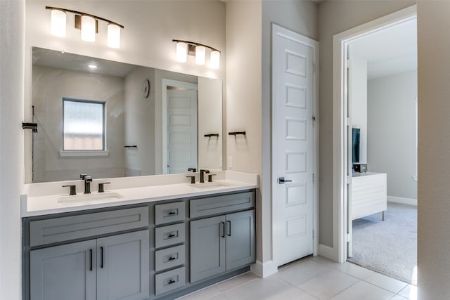 full bathroom with a sink, baseboards, double vanity, and tile patterned floors