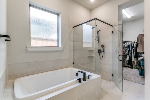 bathroom with a walk in closet, a garden tub, a stall shower, and tile patterned flooring